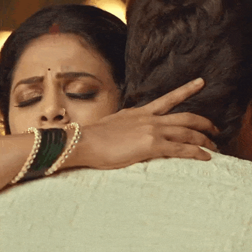a woman is hugging a man with her hand on his head