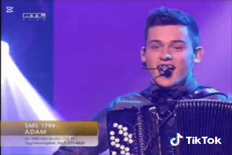 a young man singing into a microphone while playing an accordion on a stage