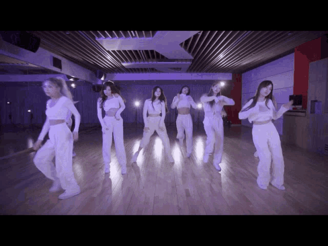 a group of young women are dancing in a dark room