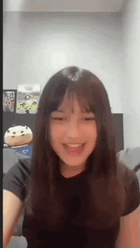 a young girl is sitting on a couch in a room with a stuffed animal in the background .
