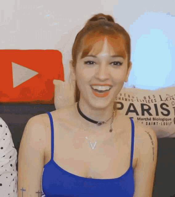 a woman wearing a blue tank top is smiling in front of a paris pillow
