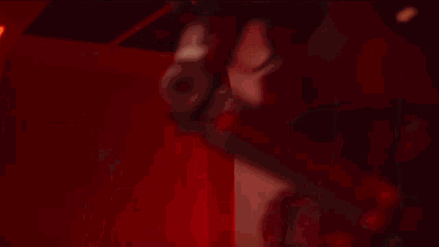 a man with a beard is holding a gun in front of a red wall