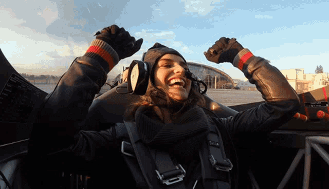 a woman in a pilot 's seat with her arms up