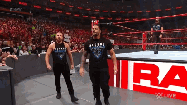 two wrestlers wearing hounds t-shirts walk out of the ring