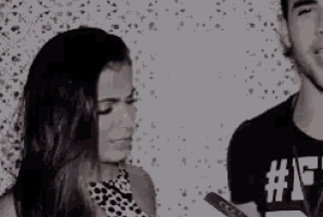 a man and a woman are standing next to each other talking to each other .