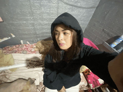 a woman wearing a black hoodie is taking a picture of herself