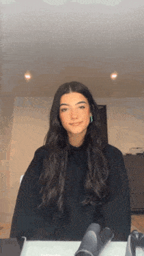 a girl with long dark hair is sitting at a table