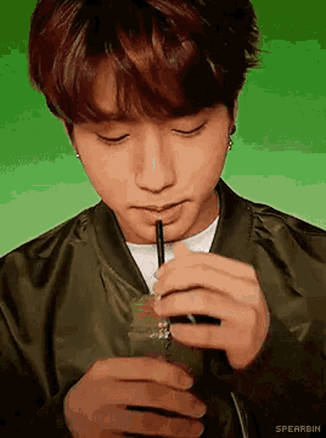 a young man is drinking through a straw from a plastic cup .