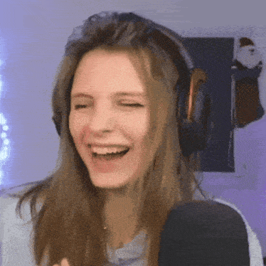 a woman wearing headphones is laughing in front of a microphone