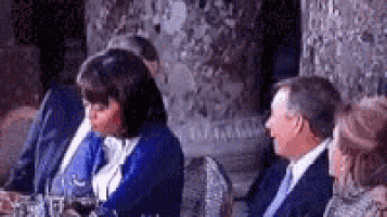 a group of people are sitting at a table and talking .