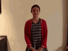 a woman wearing a red cardigan and a black and white checkered dress