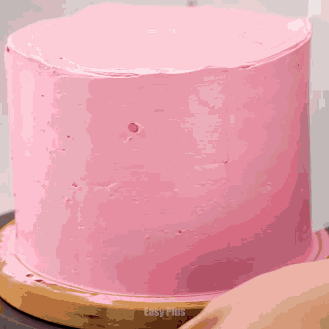 a pink cake is being decorated with chocolate dripping down the side