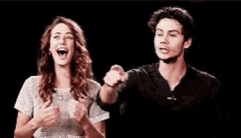 a man and a woman are laughing and pointing at each other while standing next to each other .
