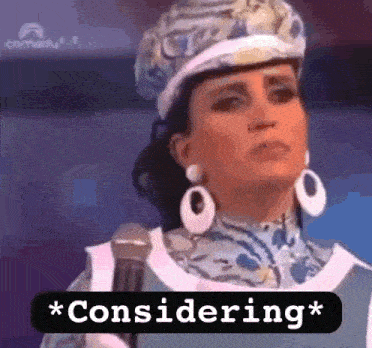a woman wearing a hat and earrings is standing in front of a microphone and saying `` considering '' .