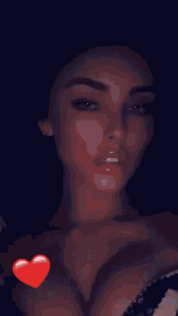 a close up of a woman with a red heart on her chest