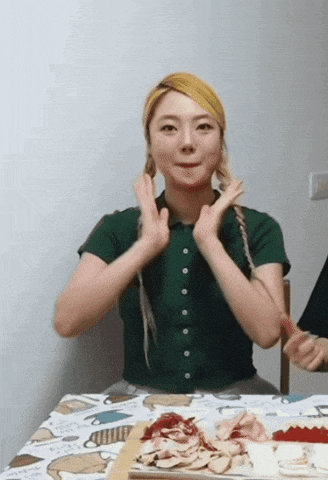 a woman in a green shirt is sitting at a table with a plate of food on it