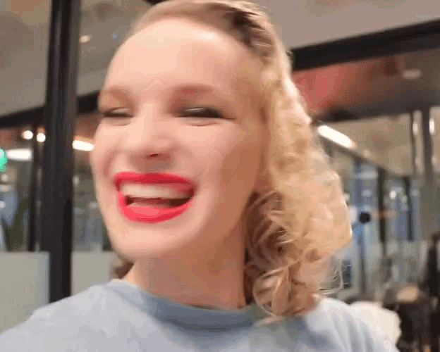 a woman with red lipstick on her lips is smiling and looking at the camera .