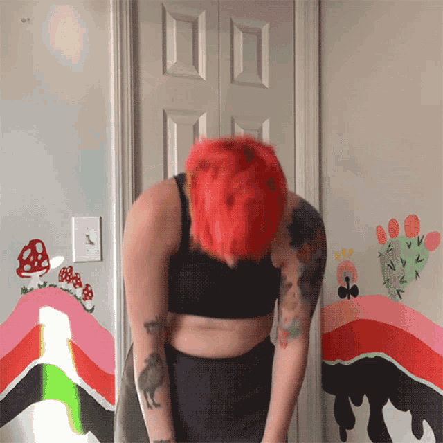 a woman with red hair and tattoos stands in front of a painting