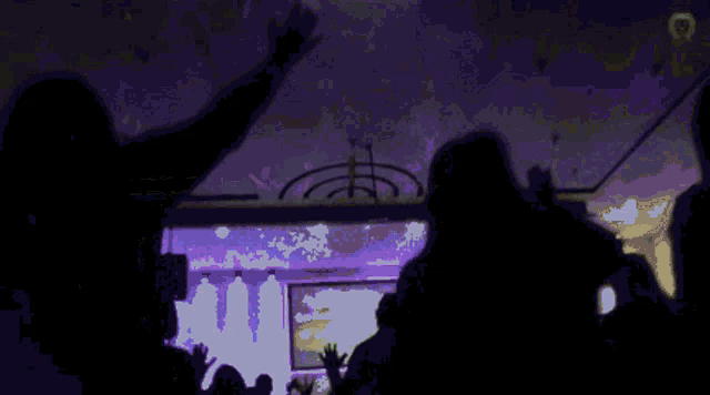 a group of people are standing in a dark room with purple lights