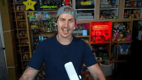 a man with a mustache is holding a wii remote in front of a nintendo sign