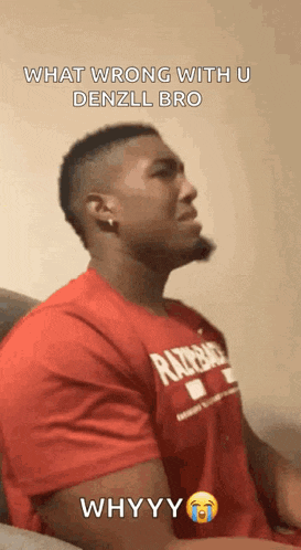 a man in a red shirt is sitting on a couch with his eyes closed .