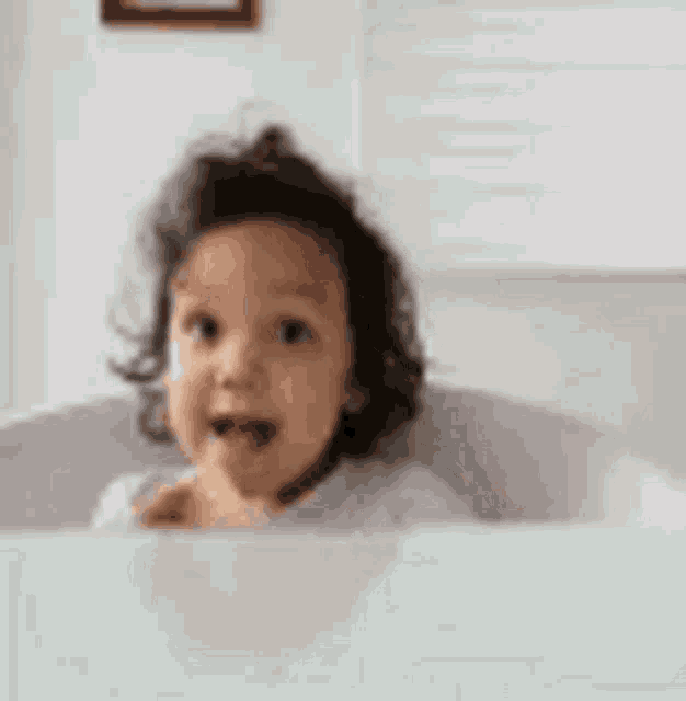 a baby is sitting in a bathtub and giving a thumbs up sign .