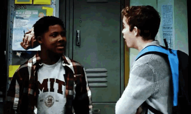 a man wearing a shirt that says mit talks to another man