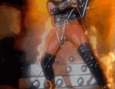 a man playing a guitar in front of a fire background