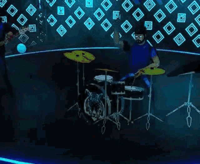 a man is playing drums in a dark room while another man plays guitar .