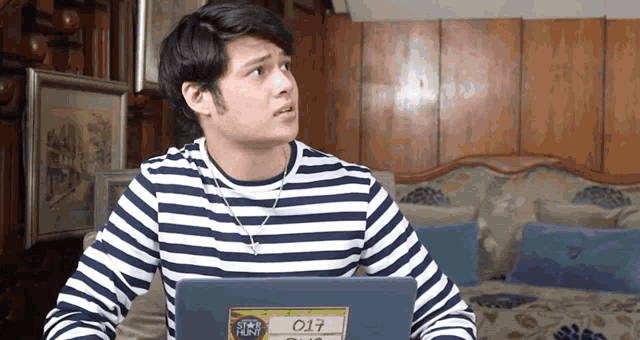 a man wearing a striped shirt has a sticker on his laptop that says ' star hunt '