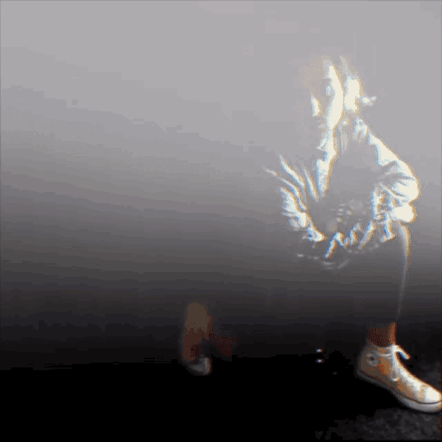a person wearing converse shoes sits on the floor