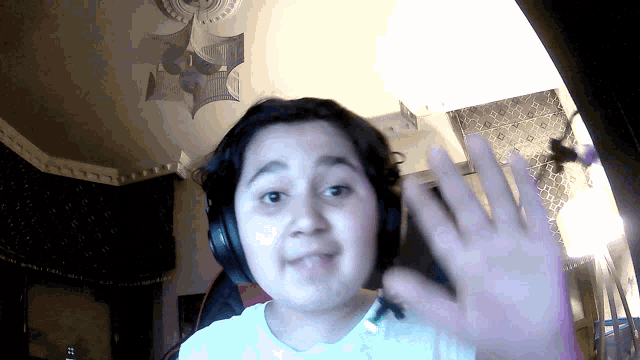 a young girl wearing headphones and a white shirt waves her hand