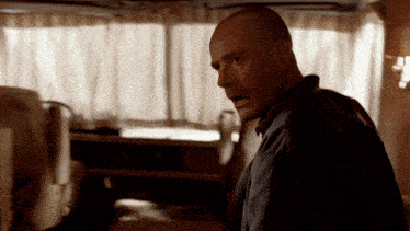 a man with a shaved head stands in a dark room