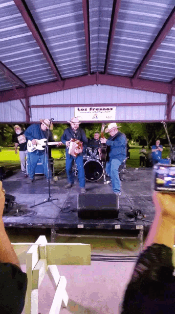 a band is playing under a covered area with a sign that says los franes on it