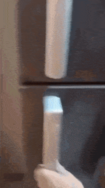 a person is opening the door of a refrigerator and taking a bottle out of it .