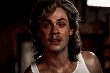 a man with long hair and a mustache is wearing a tank top .