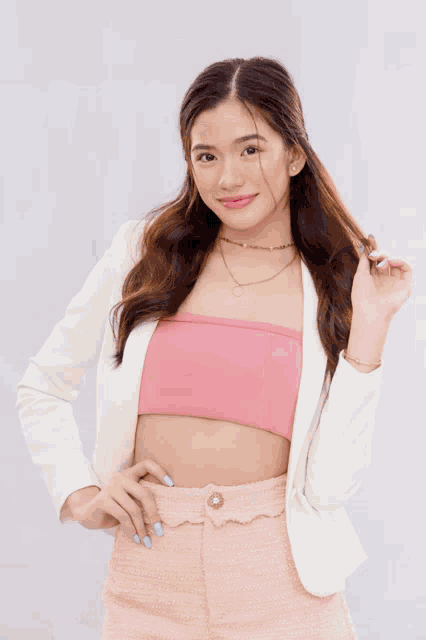 a woman wearing a pink blazer and white skirt smiles