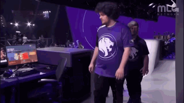 a man wearing a purple shirt with a white lion on it