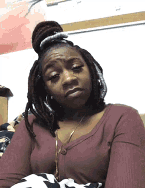 a woman with dreadlocks is wearing a purple sweater