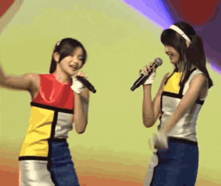 a woman singing into a microphone while another woman looks on