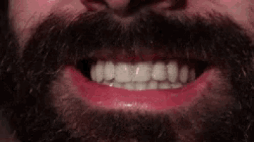 a close up of a man 's mouth with a beard and red lipstick on his lips .