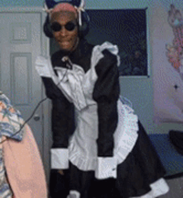 a man wearing a maid costume and headphones is standing in a room .