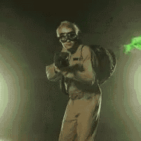a man in a ghostbusters costume is holding a gun in a dark room