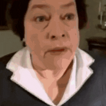 a close up of a woman 's face with a white collar and a black jacket .