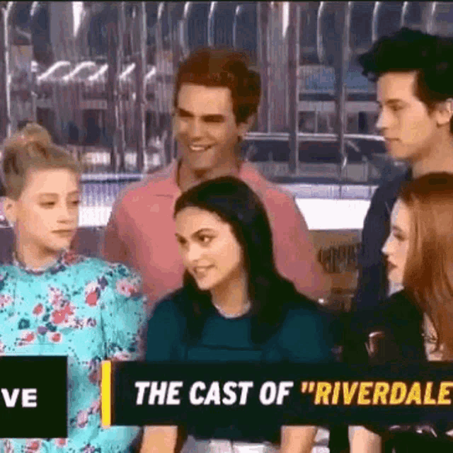 a group of people standing next to each other with a sign that says `` the cast of riverdale '' .