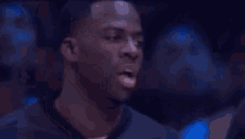 a man is smiling in a dark room with a blurry background .