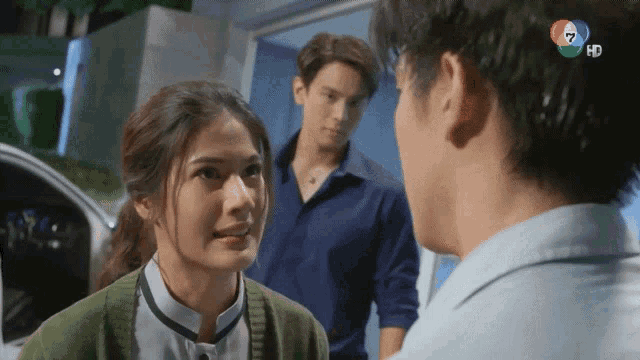 a woman in a green sweater talks to a man in a blue shirt with the number 7 on his shirt