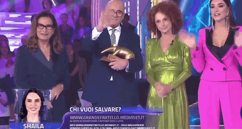 a woman named shaila is standing next to a man in a suit on a stage