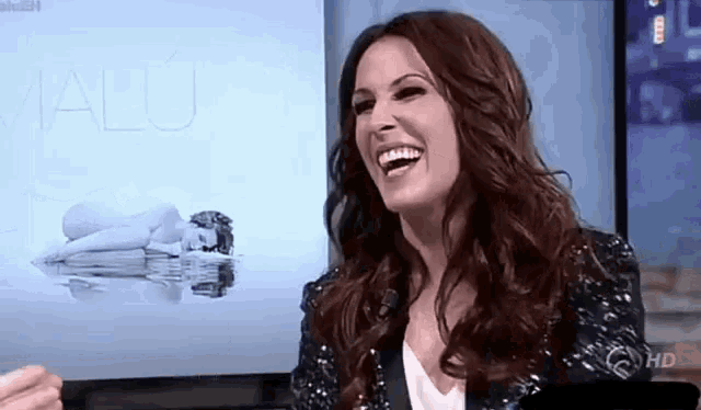 a woman is laughing in front of a screen that says alu