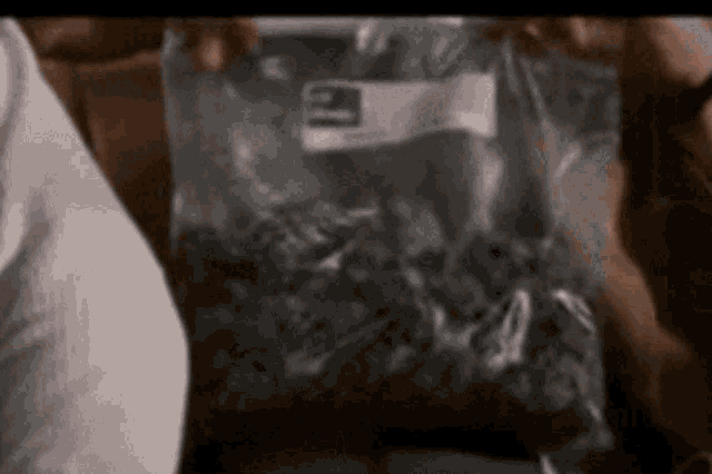 a person is holding a bag of marijuana with the number 3 on it